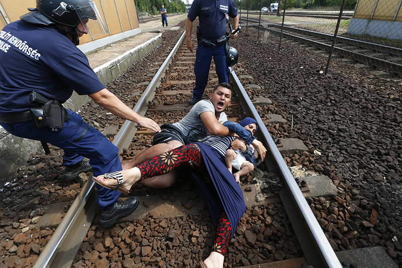 Венгерские полицейские и&nbsp;семья мигрантов после&nbsp;остановки поезда близ&nbsp;лагеря для&nbsp;беженцев недалеко&nbsp;от&nbsp;столицы Венгрии