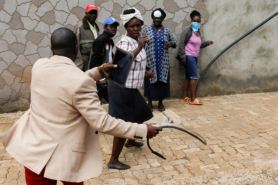 Чиновник кнутом разгоняет граждан, пришедших за продовольственным пайком, для создания между ними дистанции. Найроби, Кения

