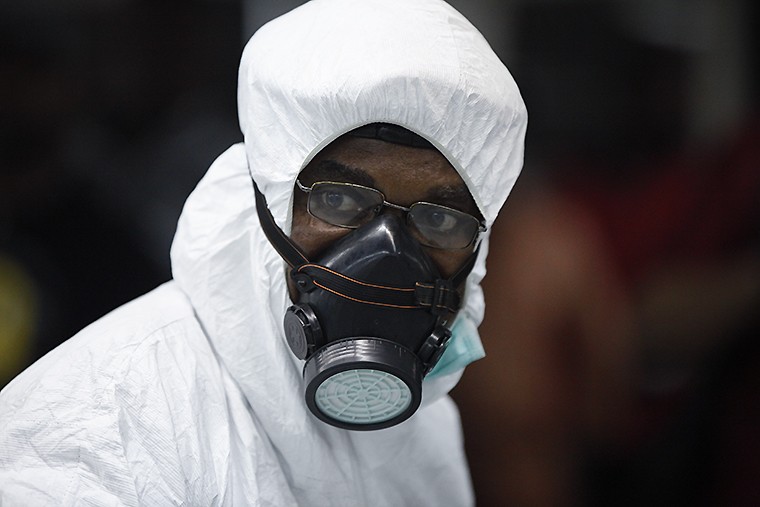 Нигерийский чиновник надел защитную маску в зале прибытия международного аэропорта имени Мухаммеда в Лагосе. По последним данным Всемирной организации здравоохранения (ВОЗ), от лихорадки Эбола погибло 932 человека. 