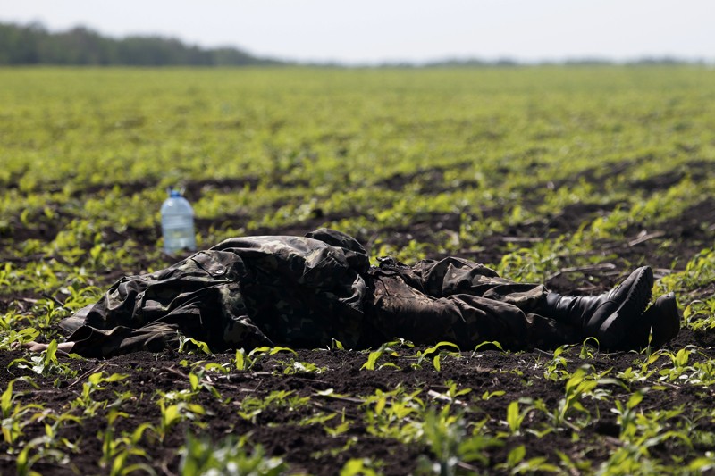 Тело, покрытое униформой, лежит в поле недалеко от деревни Благодатное на востоке Украины. 