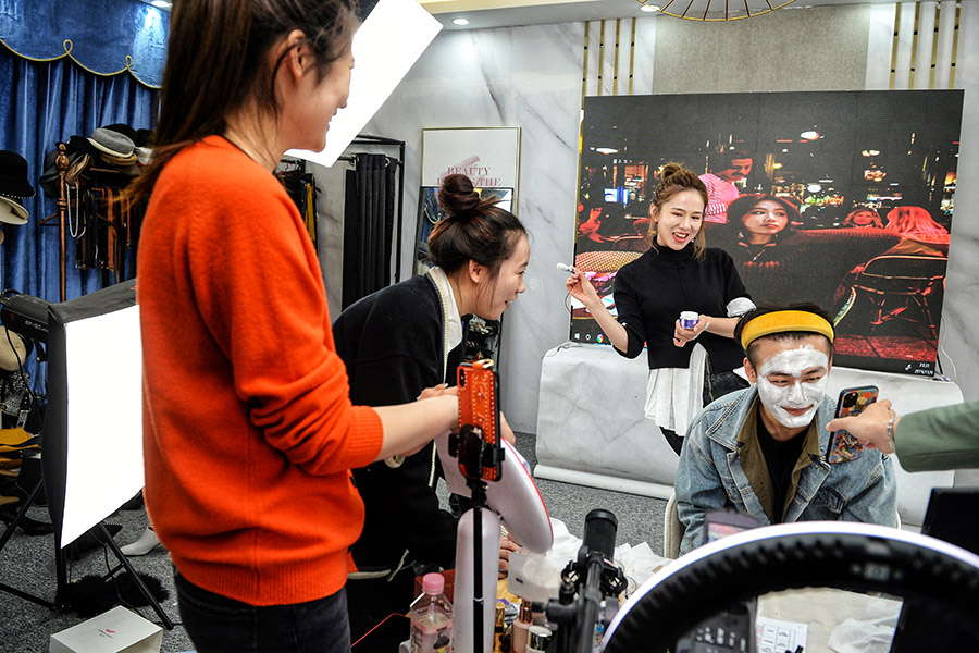 Ведущий прямой трансляции и его помощники рекламируют маску для лица перед началом продаж в день холостяка
