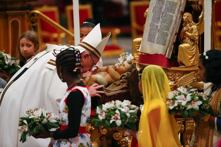Папа римский Франциск целует скульптуру младенца Иисуса на мессе в базилике Святого Петра в сочельник в Ватикане
