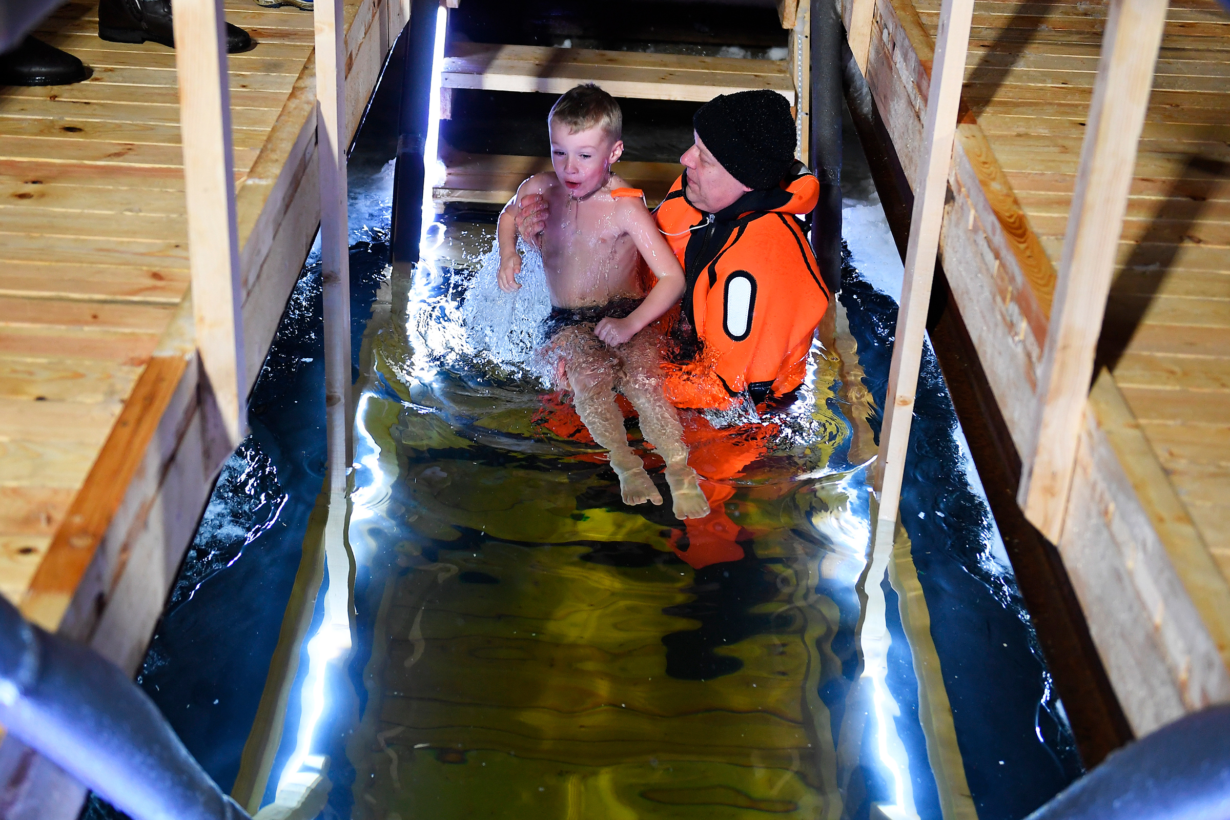 Сотрудник Московской городской спасательной службы страхует ребенка во время крещенских купаний в Москве