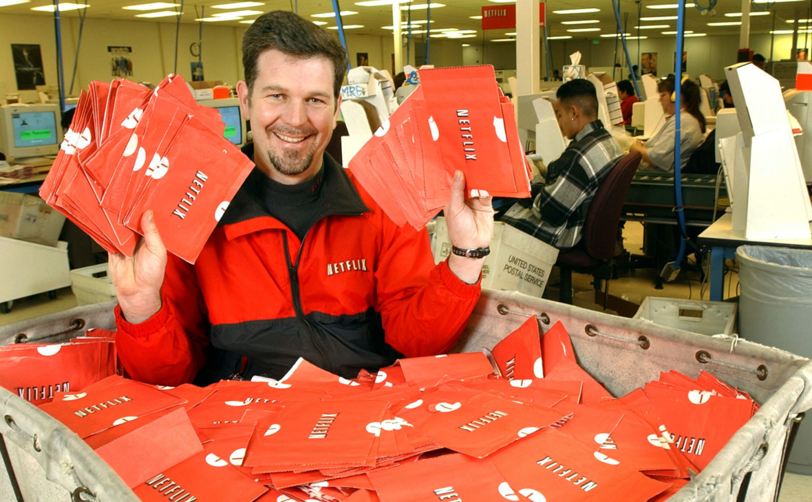 Генеральный директор Netflix Рид Хастингс​ сидит в тележке, полной готовых к отправке DVD-дисков 29 января 2002 года в Сан-Хосе, Калифорния, США