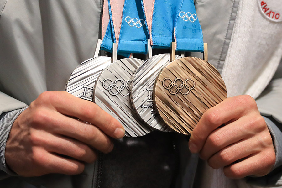Олимпийские медали в руках у российского лыжника Александра Большунова