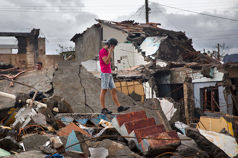 Мужчина разговаривает по телефону на обломках своего дома в Баракоа (Куба), разрушенного в результате урагана
