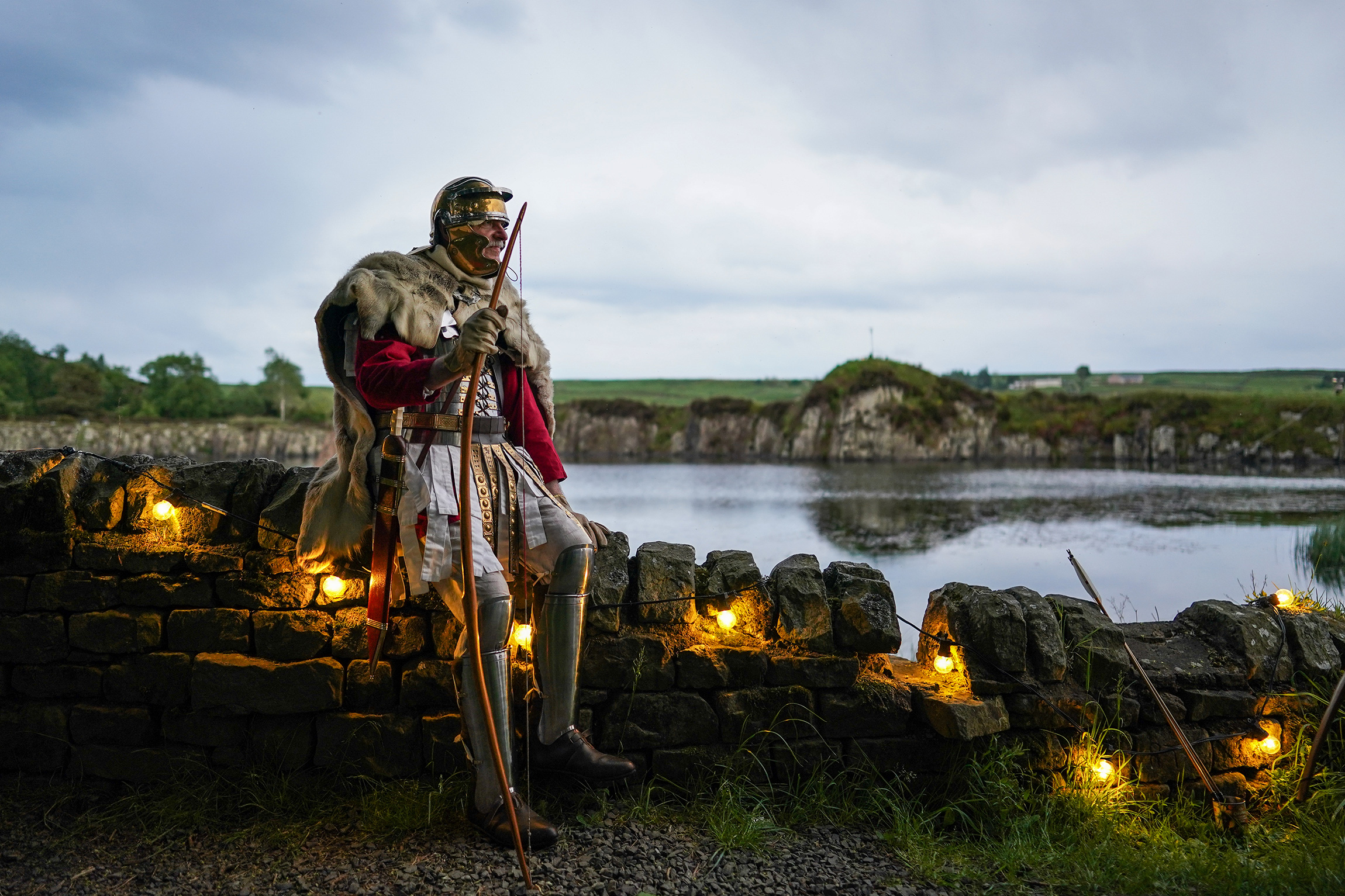 Халтвисл, Англия, 2 июня. Мужчина в костюме римского лучника готовится пустить горящую стрелу, чтобы зажечь плавучий маяк на озере