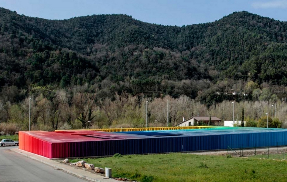 Строгую геометрию здания муниципального детского сада разбавляют разноцветные вертикальные трубки (некоторые из них вращаются) разного диаметра, из которых выполнены фасады