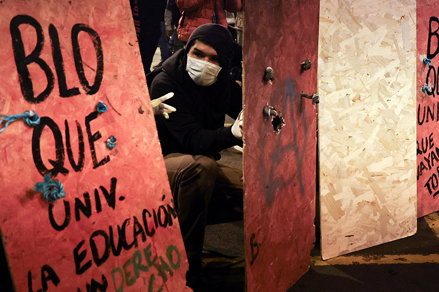Протестующий прячется за щитом с лозунгом о свободе образования в Лиме

