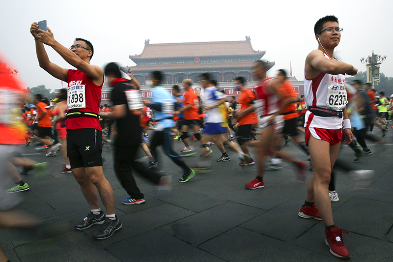 Участник марафона фотографирует себя на площади Тяньаньмэнь.