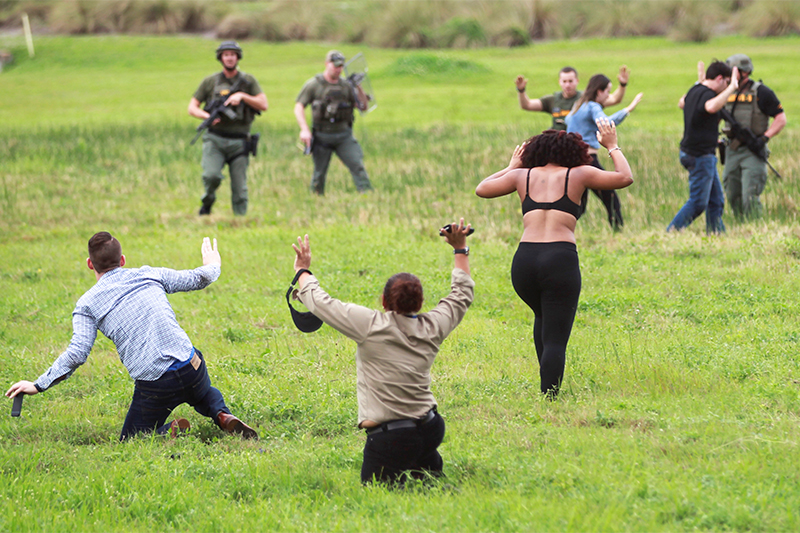 Офицеры полиции встречают людей, выбежавших на поле возле аэропорта после стрельбы