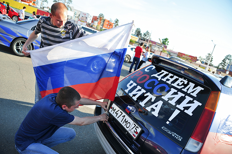 Автолюбители в Чите устанавливают флаг России на автомобиль перед пробегом, приуроченным к празднованию Дня России