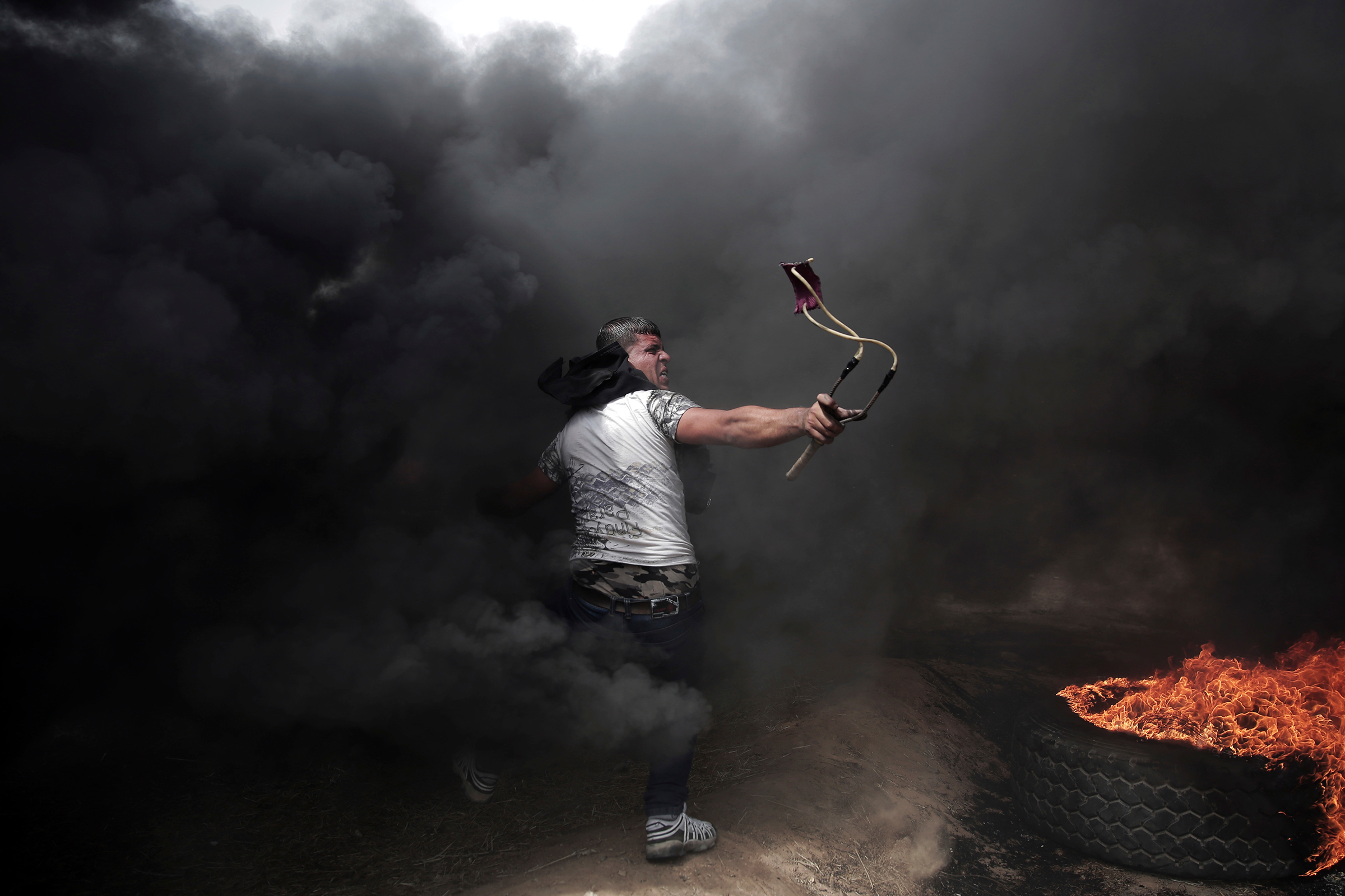 Апрель. Палестинец&nbsp;бросает камни в израильских военных на границе сектора Газа
