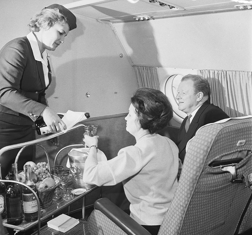 Алкоголь начал появляться в бортовом меню еще в 1960-е годы. На этом снимке стюардесса «Аэрофлота» разливает вино пассажирам туристского класса