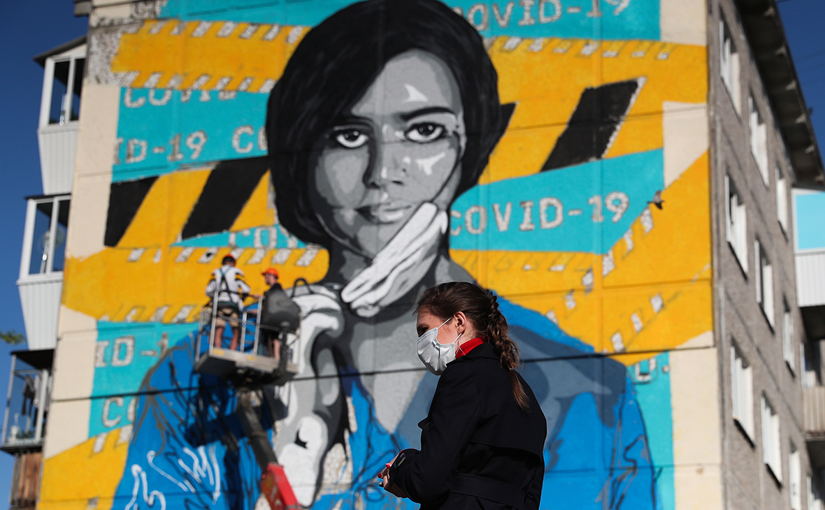 Женщина у дома с граффити в поддержку врачей, которые лечат заразившихся коронавирусной инфекцией