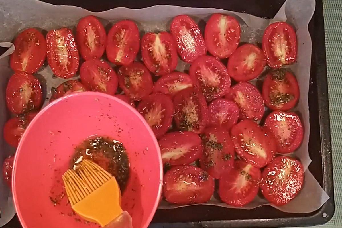 При помощи кулинарной кисти смажьте томаты оливковым маслом и отправьте в разогретую до 80 градусов духовку примерно на девять часов