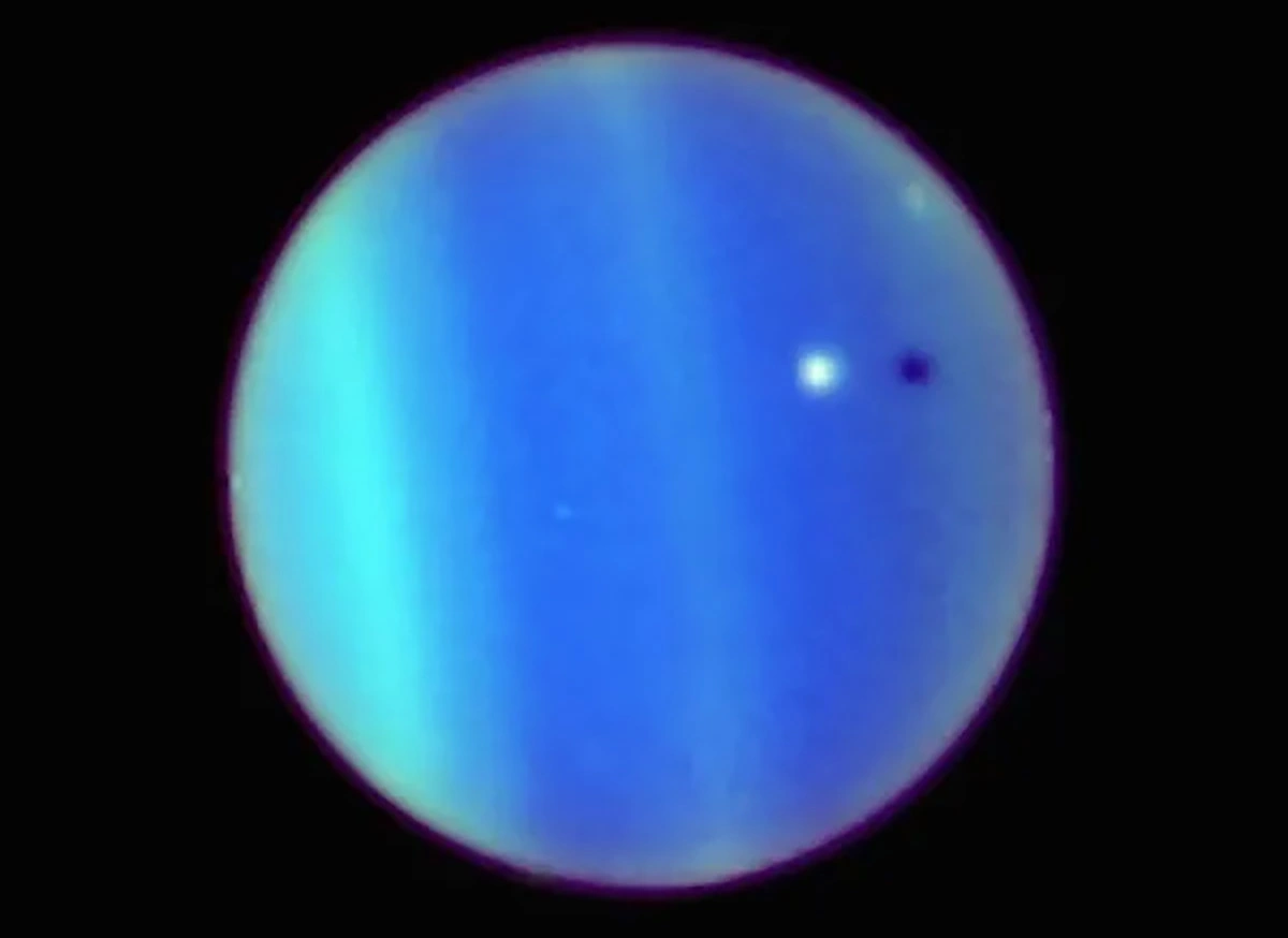 <p>Наземные телескопы легко показывают характерный зеленовато-голубой цвет Урана. На этом изображении, сделанном космическим телескопом &laquo;Хаббл&raquo; в 2006 году, также видны полосы в атмосфере и редкое прохождение спутника планеты Ариэль (белая точка) и его тени (справа)</p>