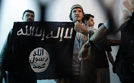 Задержанный в Йемене боевик Аль-Каиды держит флаг с надписью «Нет Бога, кроме Аллаха, и Мухаммед посланник Бога».