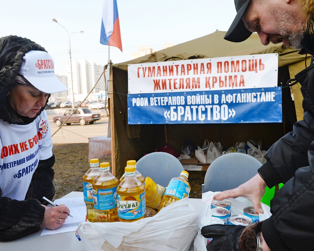 Волонтеры и прохожие у пункта сбора гуманитарной помощи жителям Крыма в Москве