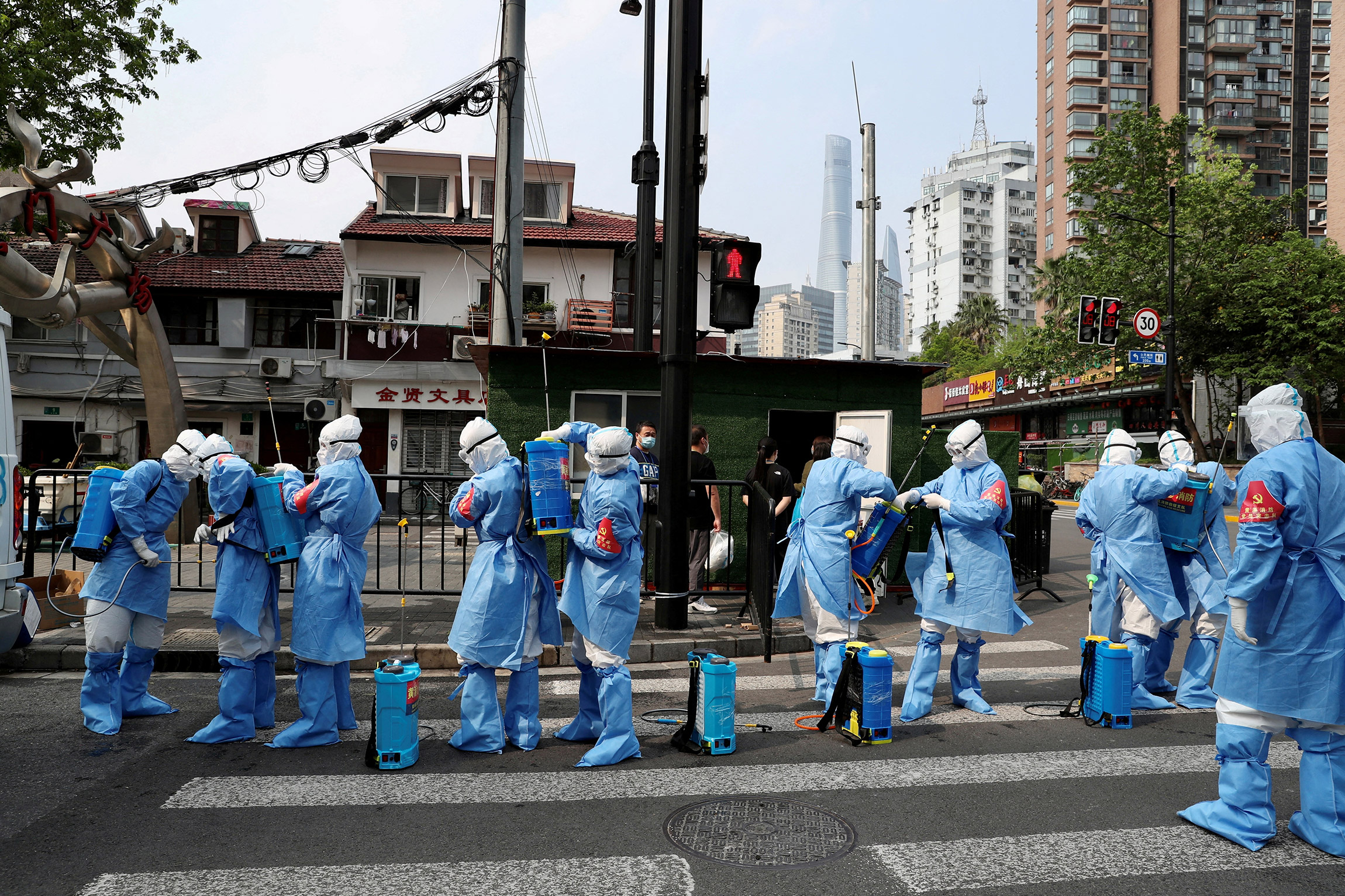 На фото: рабочие в защитных костюмах готовятся к дезинфекции жилого комплекса в районе Хуанпу, 20 апреля