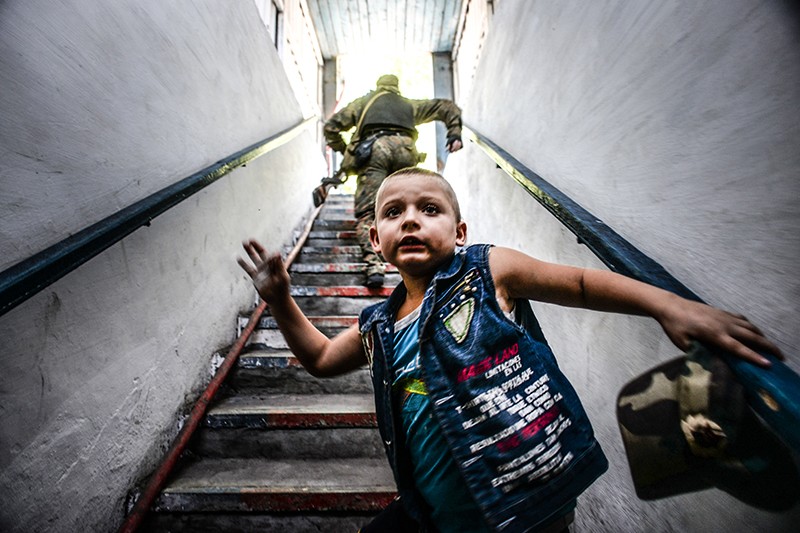 Мальчик осматривается вокруг, поднимаясь из бомбоубежища в Донецке. В этот день несколько снарядов попали в здание местного рынка и повредили находящиеся по соседству жилые дома.