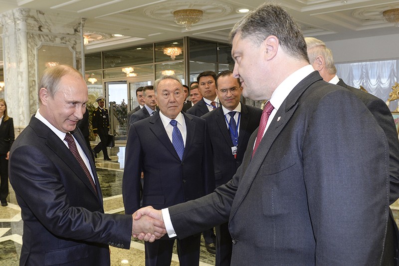 Президент России Владимир Путин и президент Украины Петр Порошенко пожимают руки на саммите в Минске.