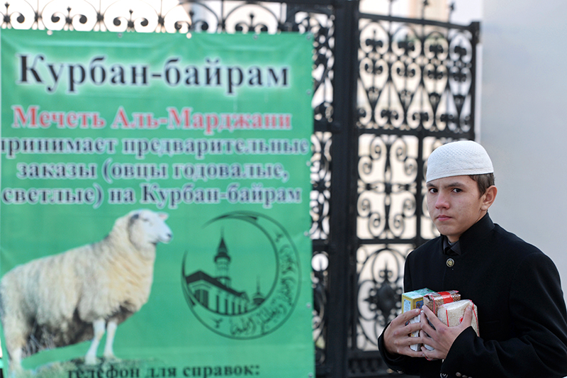 Прохожий у плаката с информацией о торговле животными для жертвоприношения на празднике Курбан-Байрам при мечети &quot;Аль-Марджани&quot; в Казани.