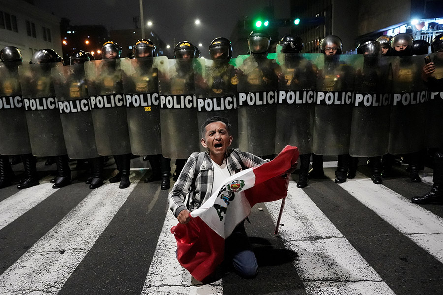 Участник протеста на коленях перед полицейскими в ходе протестов в Лиме, Перу

