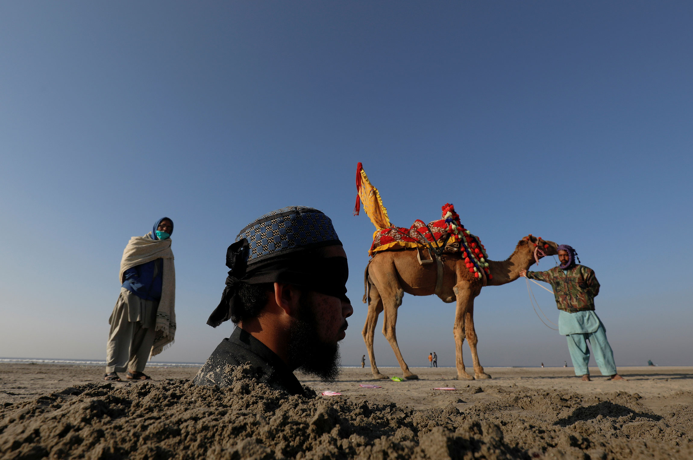 Карачи, Пакистан. Мужчина с завязанными глазами во время солнечного затмения погружен в песок: в этом регионе считают, что закапывание в песок во время затмения дает возможность исцелиться
