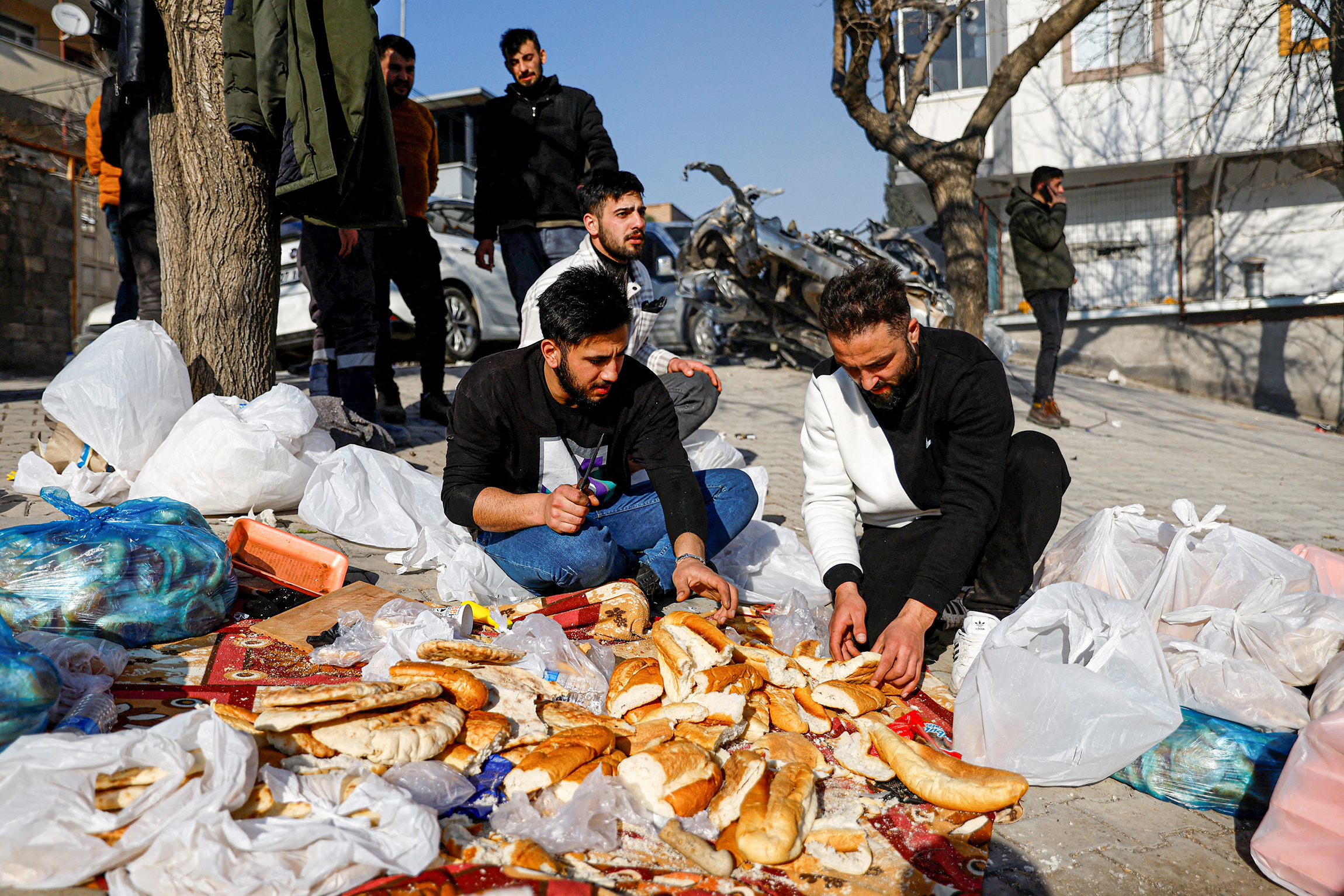 Люди готовят бутерброды на улице в турецком Кахраманмараше. Министерство национального образования Турции сообщило, что отправило 1,6 млн батонов хлеба, испеченного в пекарнях школ, в пострадавшие районы.