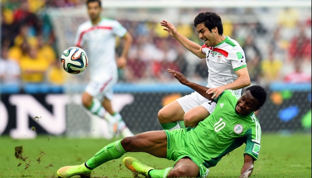 Иранец Хосро Хейдари и нигериец икел Джон Оби в борьбе за мяч  во время в матча Группе F Иран - Нигерия. 