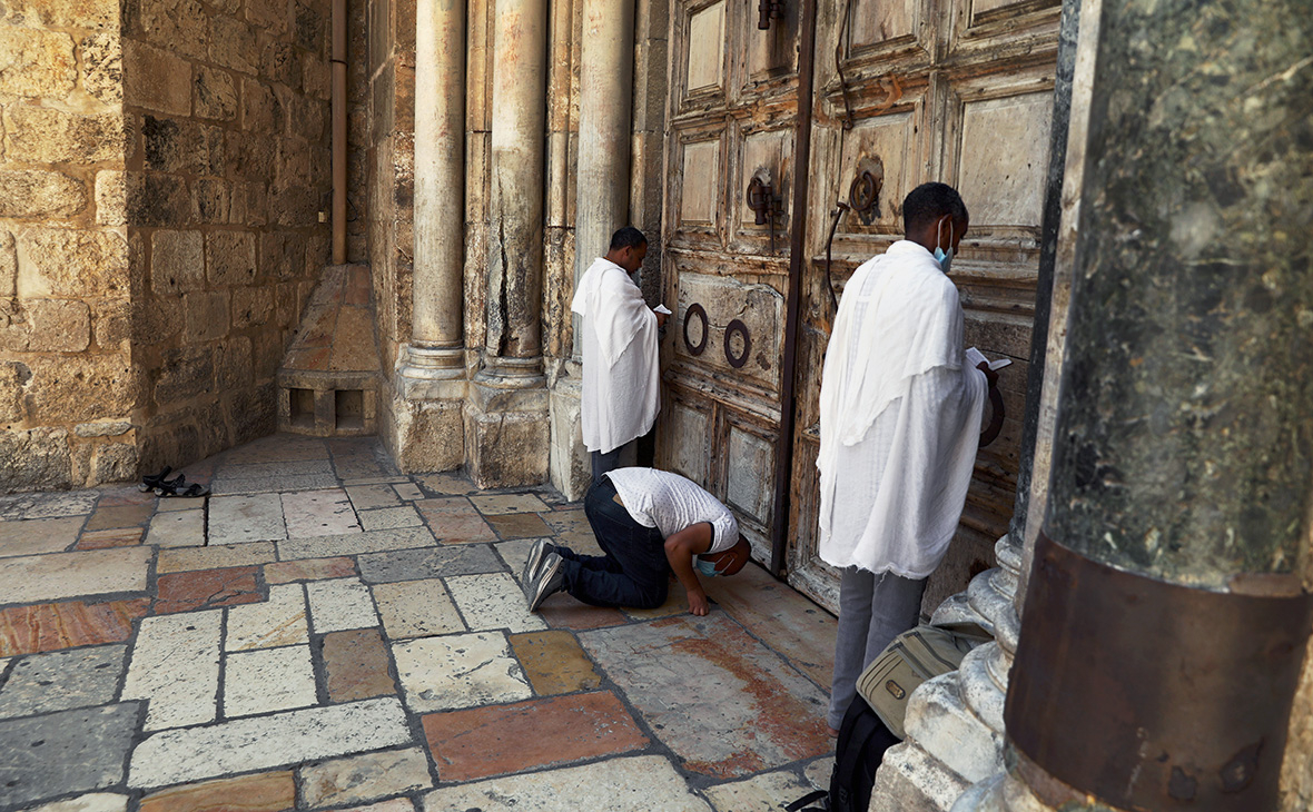 Верующие молятся рядом с закрытыми дверями Храма Гроба Господня в Старом городе Иерусалима, 10 июля 2020г.