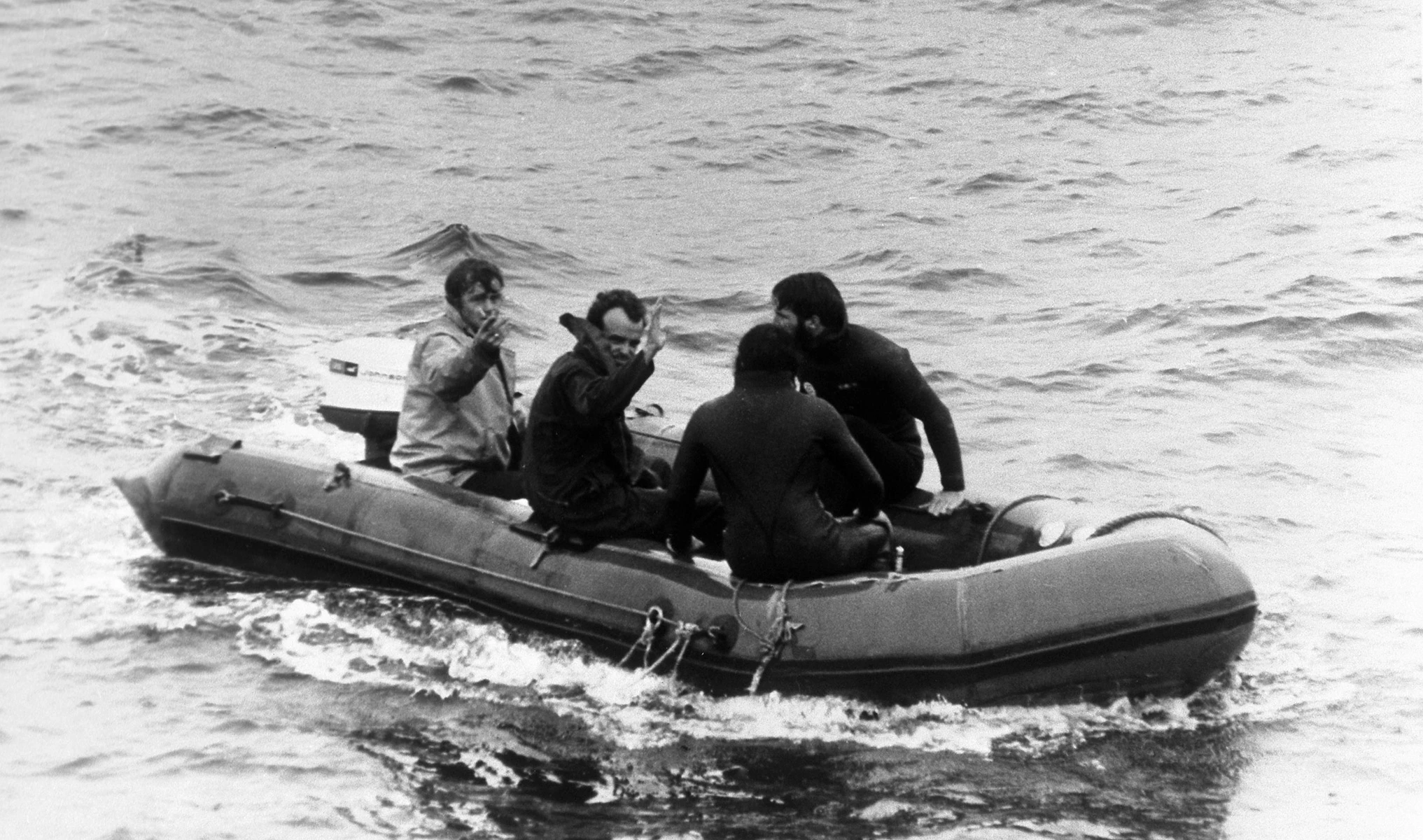 Роджер Чапмен машет рукой, когда его везут на лодке к судну Vickers Voyager