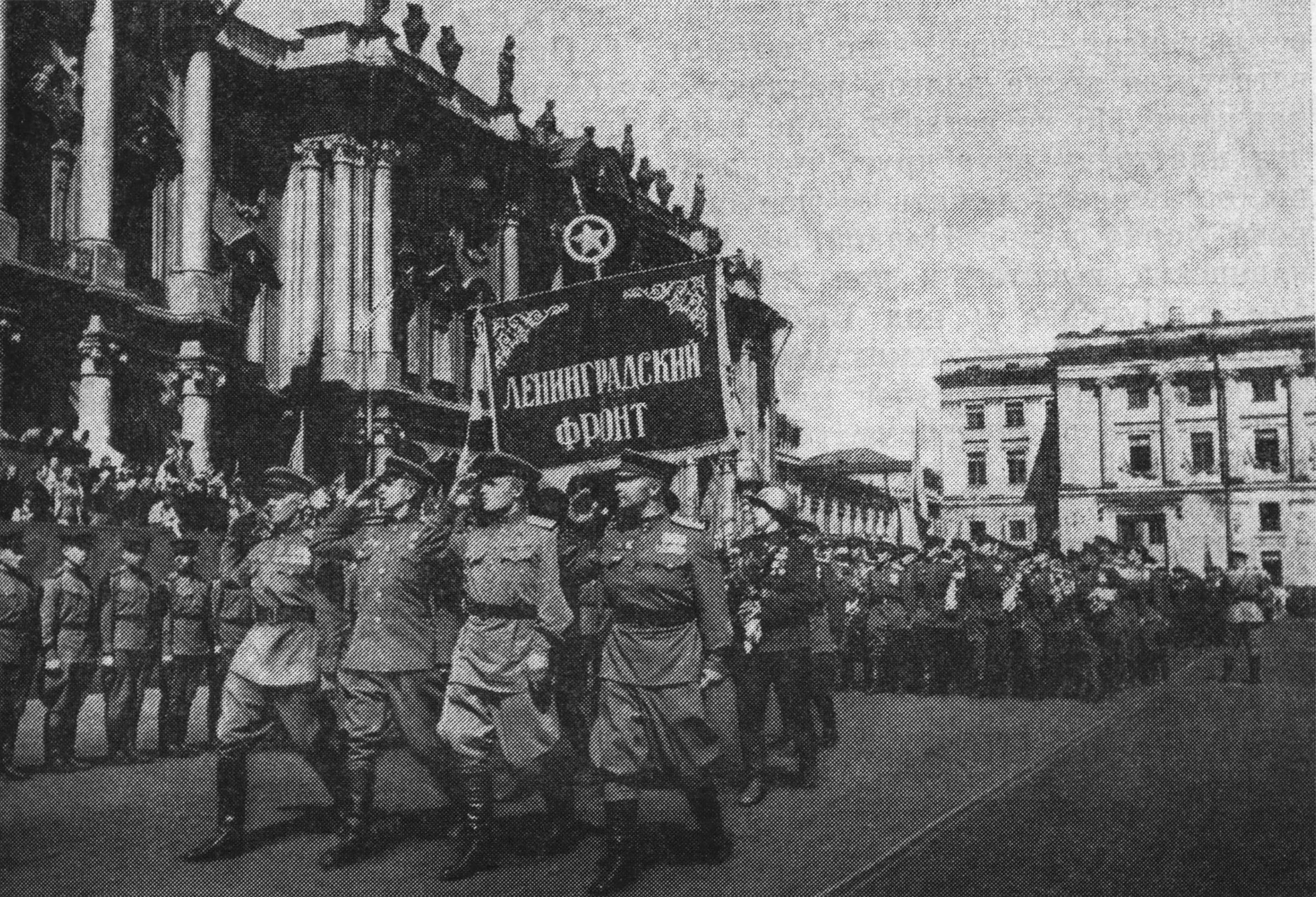 Ленинград. Возвращение бойцов Ленинградского фронта.
В домах вокруг Финляндского вокзала «даже на крышах сидели люди». «И вот далекий звук едва слышно донесся до площади, — описывалось в печати. — Он повторился, он усилился — это играл оркестр, это гвардия приближалась к площади, это непрерывные несмолкающие крики «ура!» и «слава!» сопровождали ее на пути... Как один человек, вздрогнула, рванулась навстречу многотысячная толпа. Взметнулся разноцветный вихрь букетов, и на какой-то миг все смешалось.
Могучей ленинградской гвардии, столько раз ходившей под огнем противника, вероятно, еще никогда не доводилось двигаться так медленно и осторожно. Бережно, стараясь не оттолкнуть ни одного протянутого им букета, не спугнуть ни одного ребятенка, пробирались сквозь толпу гвардейцы. Осторожно ступали умные кони, в гривах их тоже запутались цветы, на орудиях, на повозках — всюду, как стайки птиц, уже сидели ребятишки...»