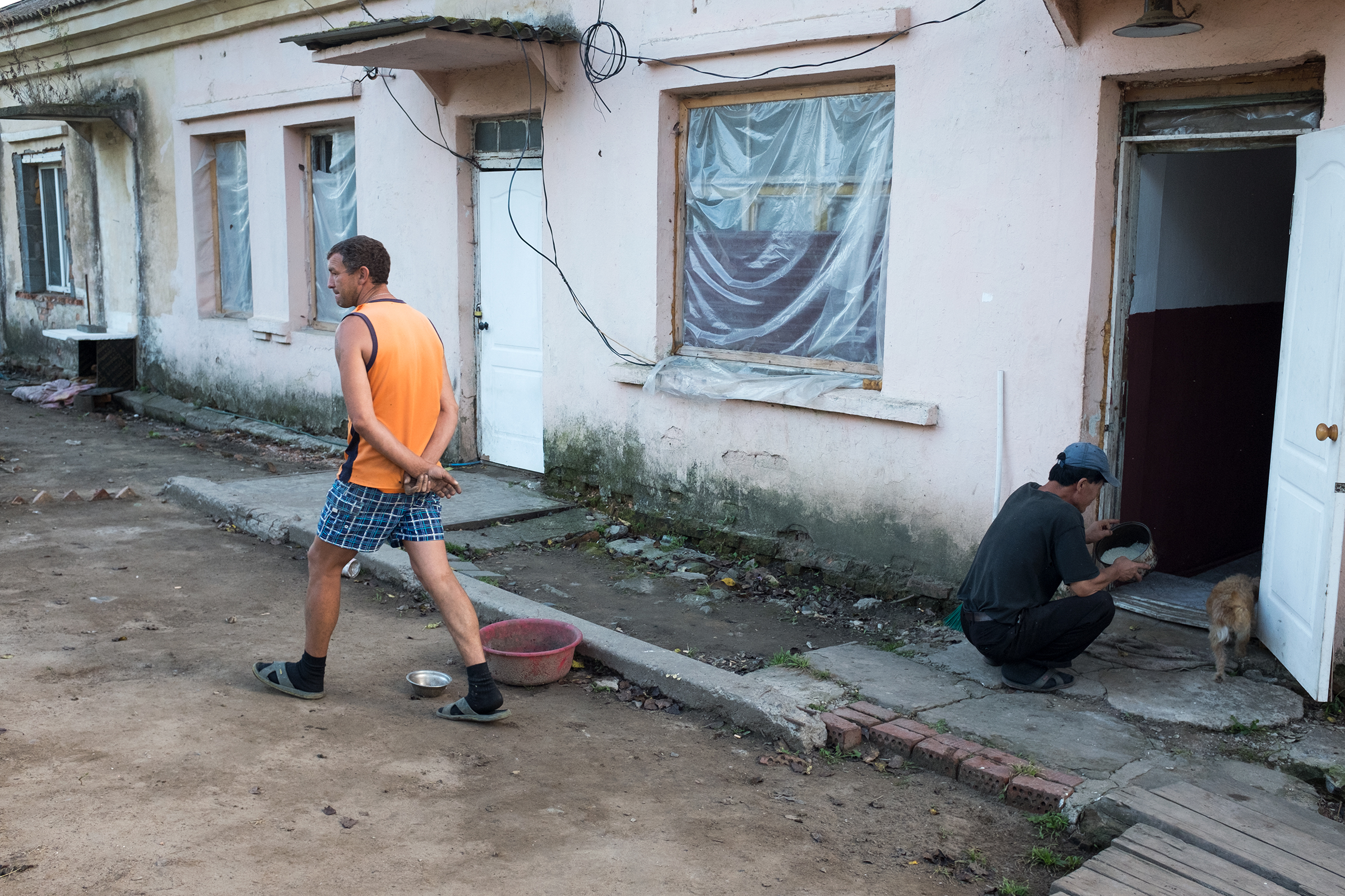 Александр Егупов (на фото слева) из Тамбова попал в Хасанский район благодаря службе в погранвойсках. Здесь он женился, а год назад ему выделили в поселке половину одноэтажного дома. Во второй половине располагается общежитие северокорейцев: сейчас в двухкомнатной квартире живет около 15 человек. Они работают на стройке в поселке.