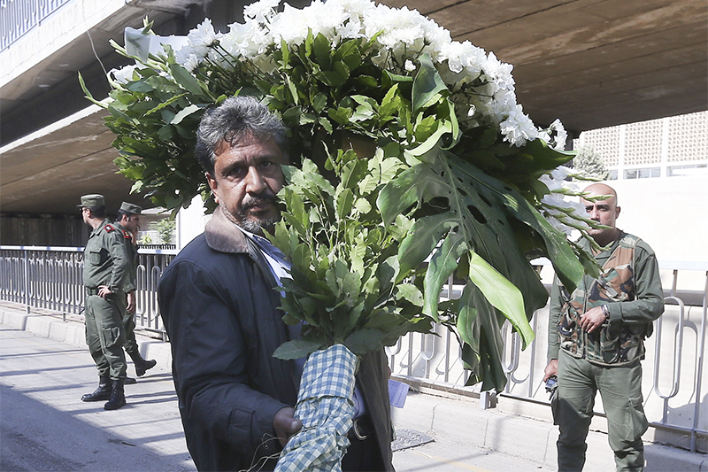 Мужчина несет цветы к российскому посольству в Дамаске в память о жертвах авиакатастрофы Airbus A321