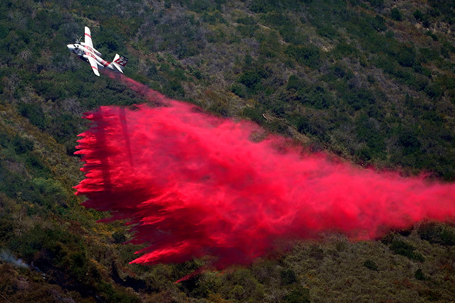 На фото:  пожарный самолет сбрасывает воду на прибрежные возгорания