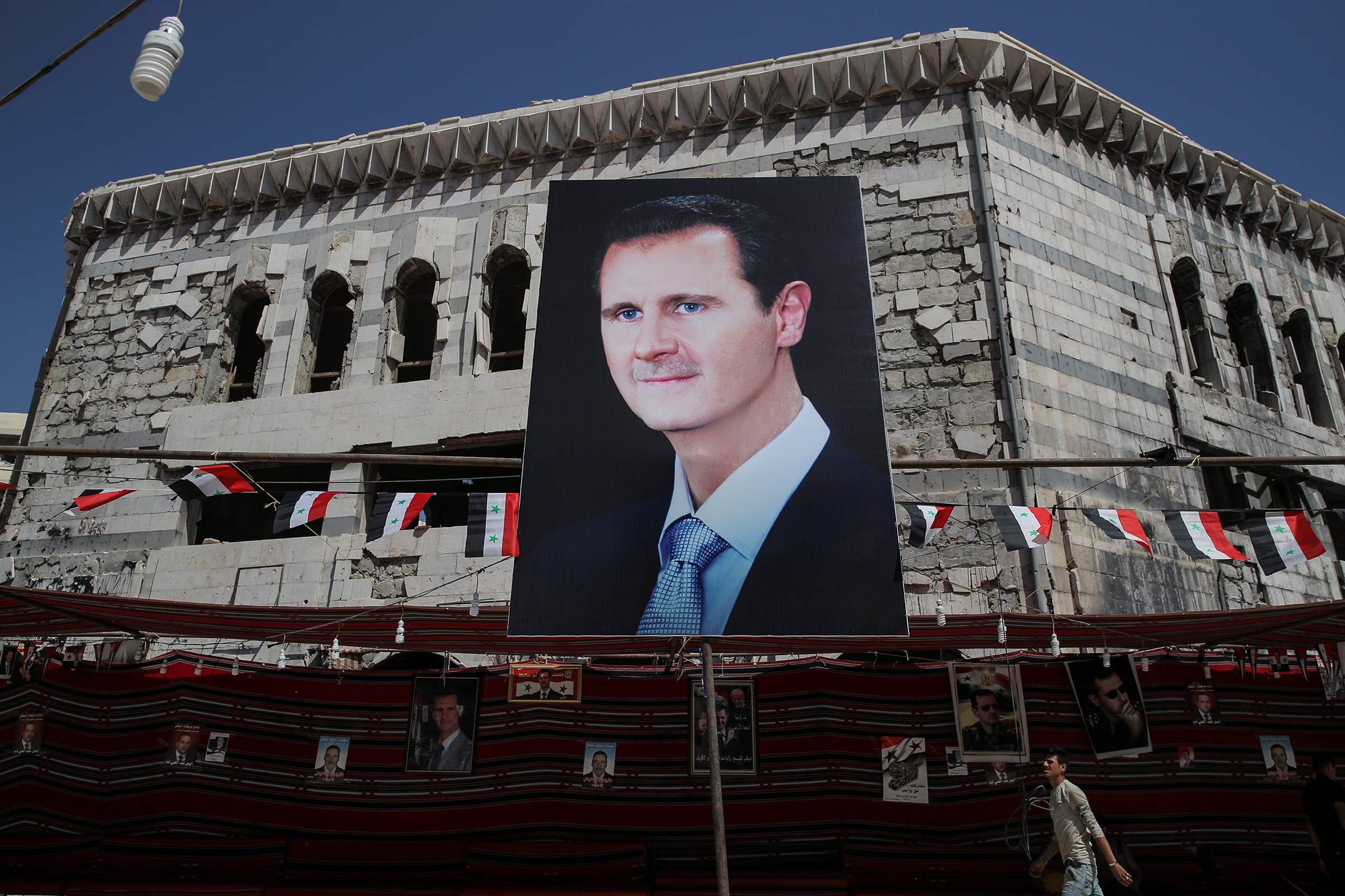 Плакат с изображением президента Сирии Башара Асада в городе Дума в 10 км к северо-западу от столицы. Этот населенный пункт в Восточной Гуте был отбит правительственными войсками у повстанцев в апреле
