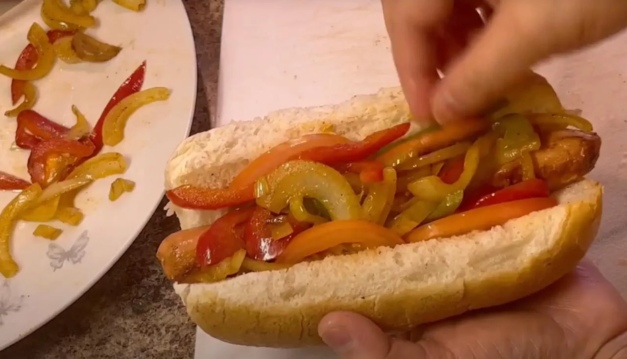 Положите сосиску и овощи в булочку