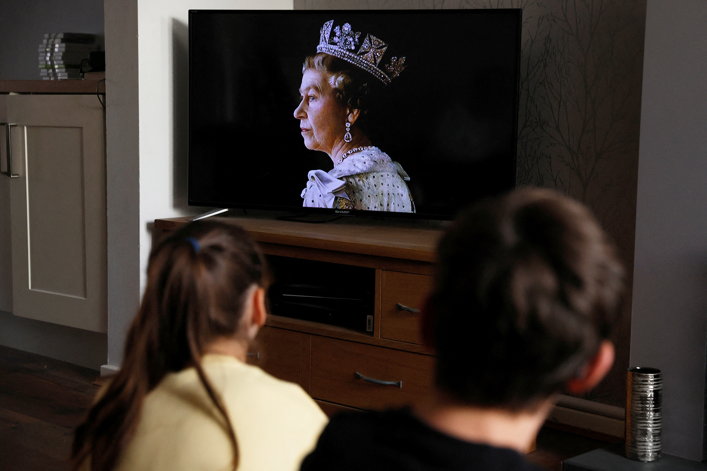Дети в Хартфорде (графство Хартфордшир, Англия) смотрят объявление по ТВ о смерти королевы