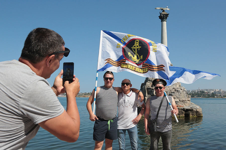 Участники празднований на фоне памятника затопленным кораблям в Севастополе