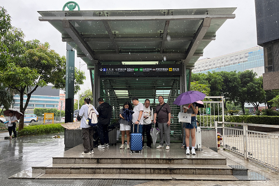 Люди прячутся от дождя у входа в метро в Шэньчжэне