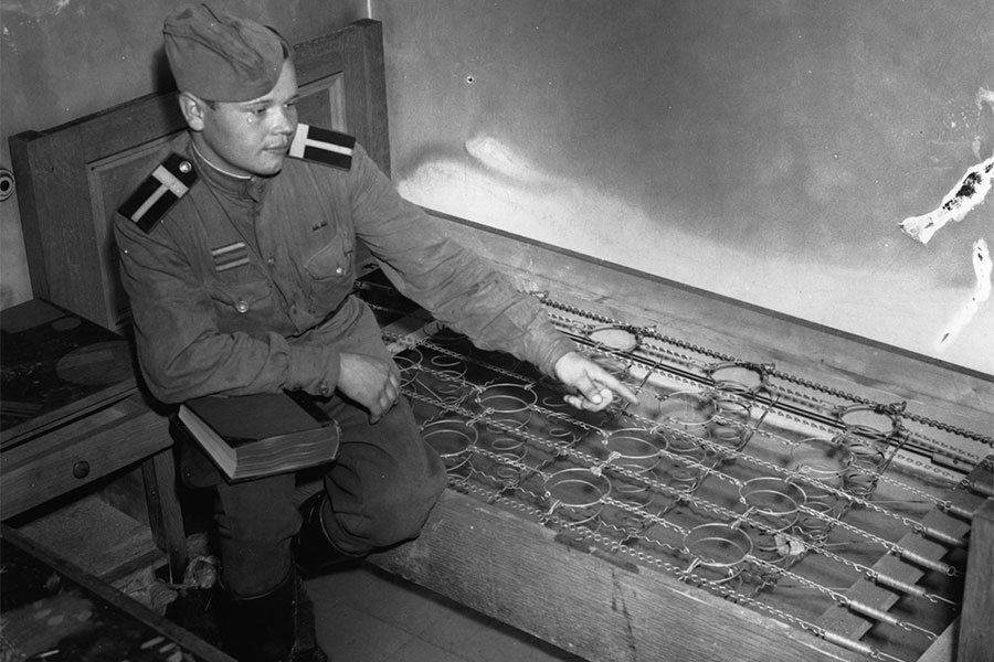 Русский солдат сидит на кровати в подвалах канцелярии Гитлера, 6 апреля 1945 года