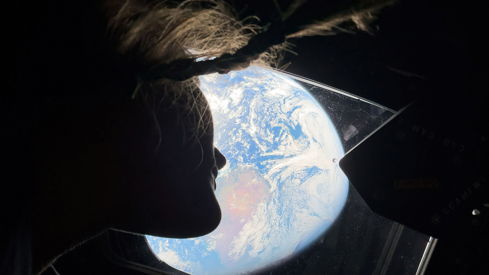 Специалист миссии «Артемида II» Кристина Кук смотрит в одно из главных окон кабины космического корабля «Орион» на Землю, пока экипаж движется к Луне