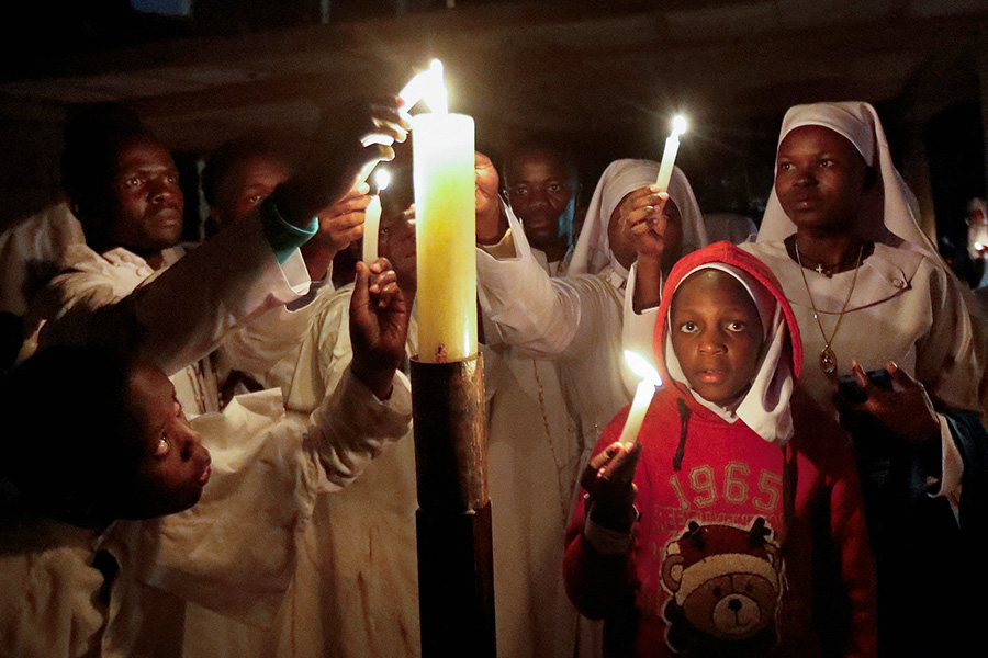 Кенийские христиане зажигают свечи во время пасхальной службы в церкви Святого Иоанна в столице страны Найроби.