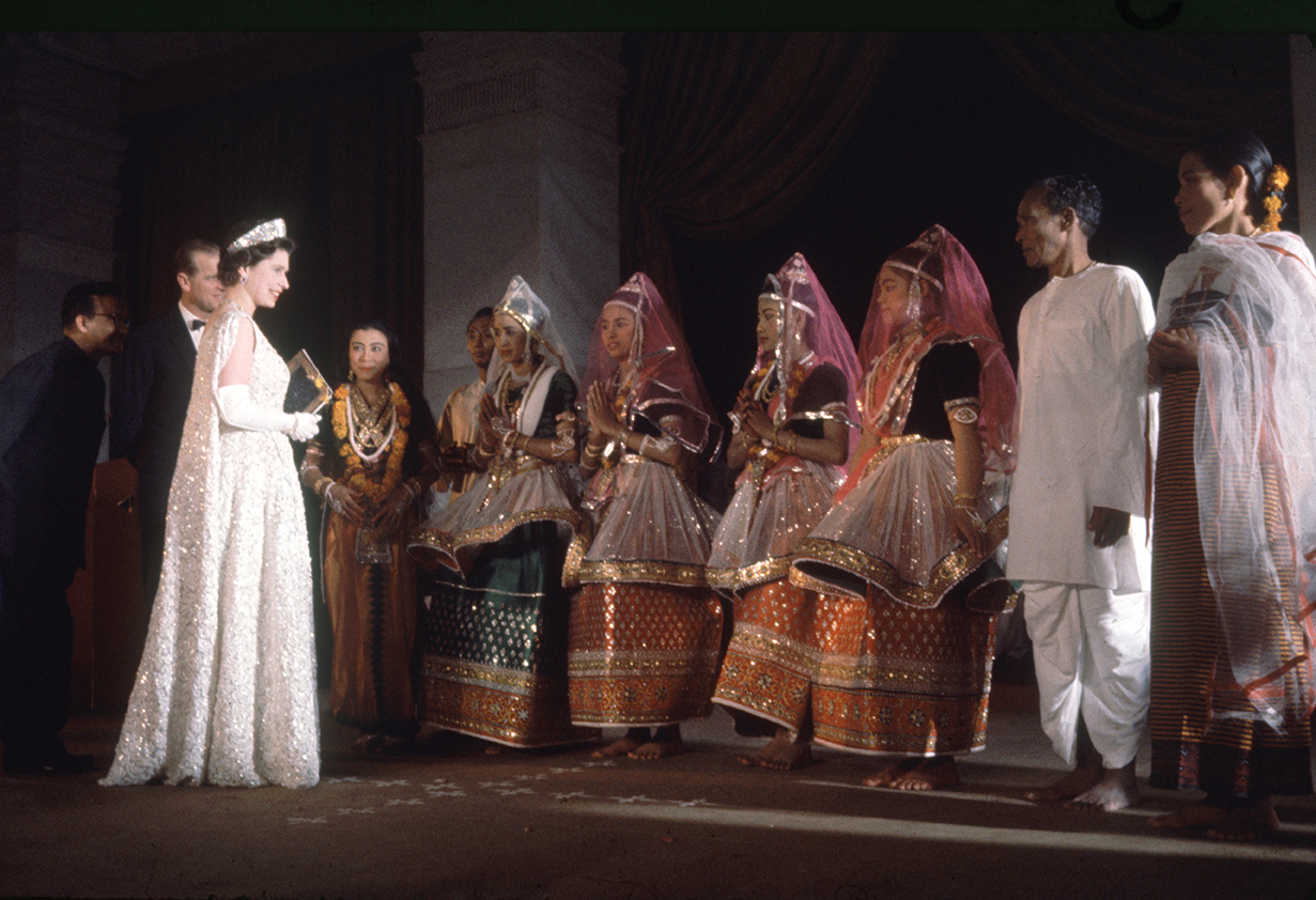 Елизавете II выбрала белое кружевное платье авторства Нормана Хартнелла с изображением цветов лотоса и сотнями жемчужин