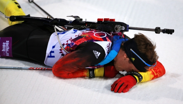 Немец Симон Шемпп из Германии падает у изнеможении на снег после финиша в индивидуальной гонке биатлонистов
