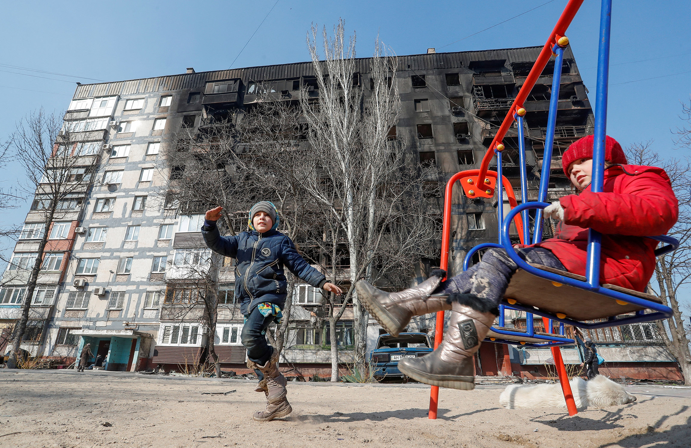 Дети играют во дворе среди разрушенных домов, 23 марта
