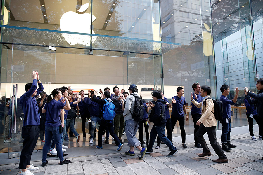 Сотрудники флагманского магазина Apple встречают покупателей, которые выстроились в очередь, чтобы купить новый iPhone X в Токио
