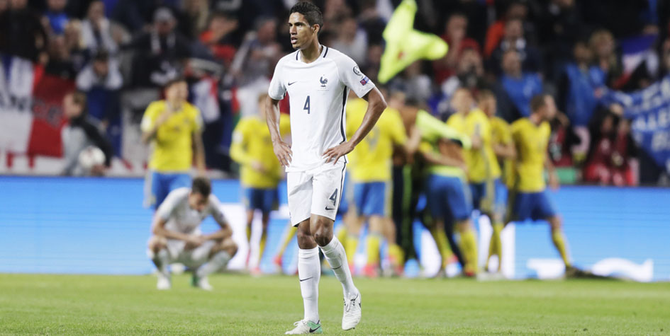 Защитник сборной Франции Рафаэль Варан на фоне празднующих победу шведских футболистов